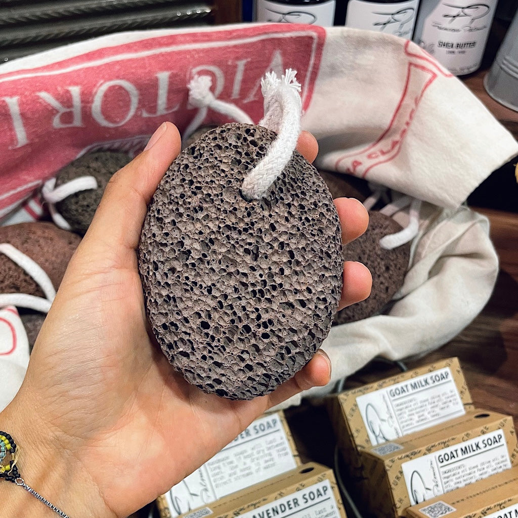 Close-up of a lava stone being used to scrub calloused feet in the bath.